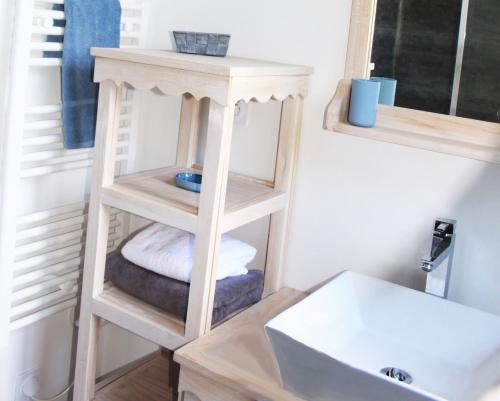 - une salle de bains avec une étagère en bois à côté d'un lavabo dans l'établissement Maison vue exeptionnelle sur la mer, à Lancieux