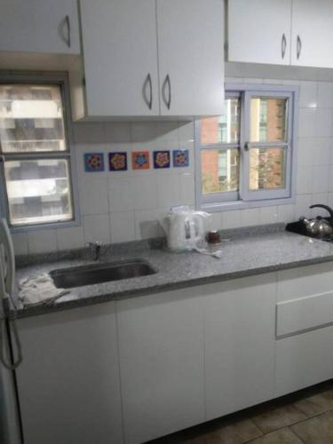 uma cozinha com armários brancos e um lavatório em Departamento Nueva Córdoba em Córdova