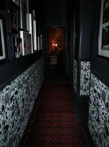 a dark hallway with a red carpet and pictures on the walls at Grewar House in Parys