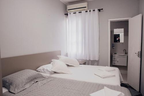 um quarto branco com uma cama e uma janela em Click Apê Centro Foz em Foz do Iguaçu