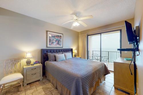 Un dormitorio con una cama y un televisor y un balcón. en Phoenix V 1213, en Orange Beach