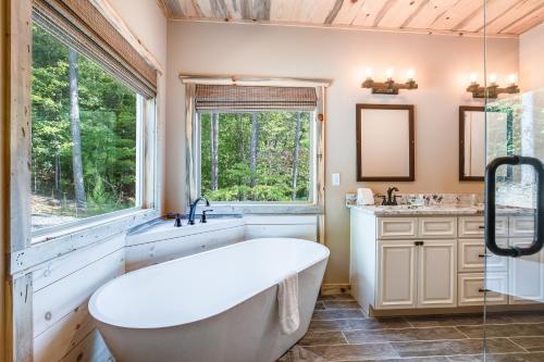 a bathroom with a tub and a sink and a window at Lofty Escape in Ellijay