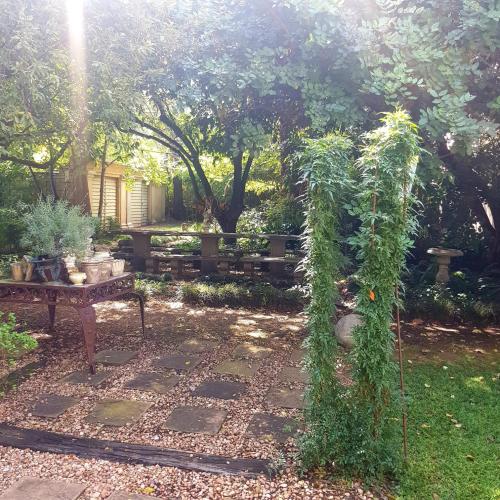 a garden with a bench and a trellis with plants at Grewar House in Parys