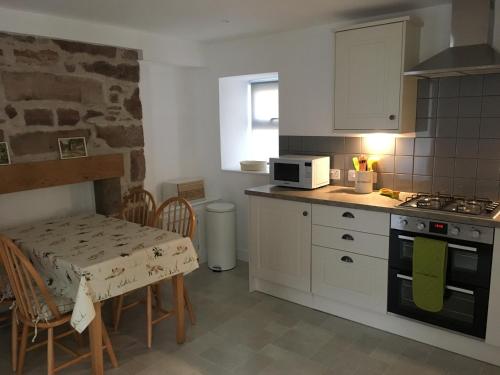 a kitchen with a table and a stove and a microwave at Kings Cottage, Nairn - a charming place to stay in Nairn