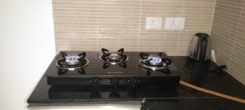 a black stove top with two tea pots on it at Lovely 1bedroom compact condo at 9th floor in Kelambākkam