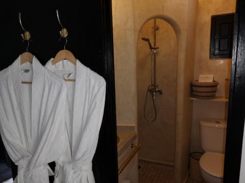 a bathroom with a shower and a white robe at Riad de charme l'Oasis d'Essaouira - Chambre Luxe in Essaouira