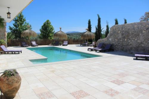 una piscina in un patio con sedie e un muro in pietra di Beautiful Accommodation At The Heart Of Andalusia a Puente Genil