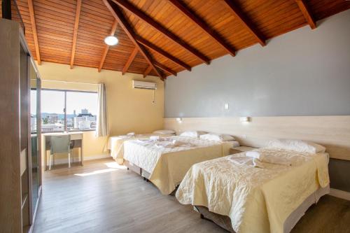 a room with three beds and a large window at Hotel Vila Mar in Florianópolis