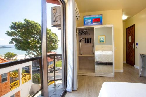 a bedroom with a view of the ocean from a balcony at Hotel Vila Mar in Florianópolis