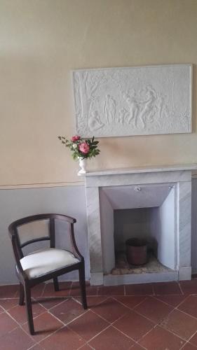 a chair sitting next to a fireplace with a vase of flowers at Casa Rovelli in Alfiano Natta
