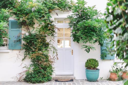 a white door with green shutters and potted plants at Domaine de Jouarre in Jouarre