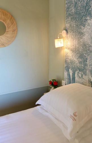a bedroom with a white bed with a painting on the wall at La Bastide du Beausset-Vieux in Le Beausset