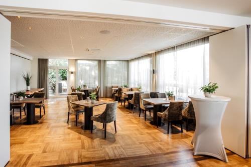 a dining room with tables and chairs and windows at Hotel Westerkamp in Osnabrück