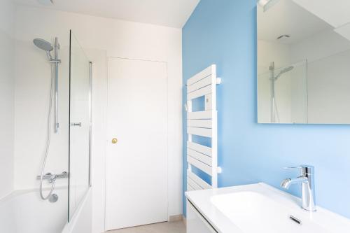Un baño blanco con ducha y lavabo. en La Grande Plage, en Saint-Cast-le-Guildo
