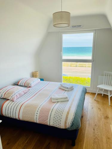 une chambre avec un lit avec vue sur l'océan dans l'établissement La Grande Plage, à Saint-Cast-le-Guildo