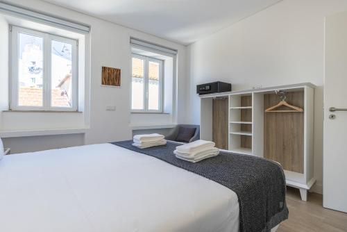 Un dormitorio blanco con una cama grande con toallas. en Garcia 28, en Lisboa