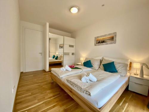 a bedroom with a large white bed with blue pillows at Apartment Seenah Zentral in Pörtschach am Wörthersee