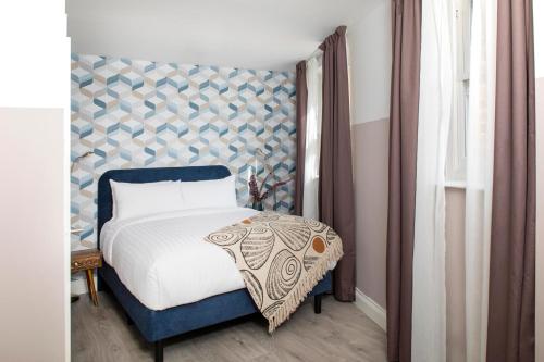 a bedroom with a bed with a blue headboard at Bob W London Spitalfields in London