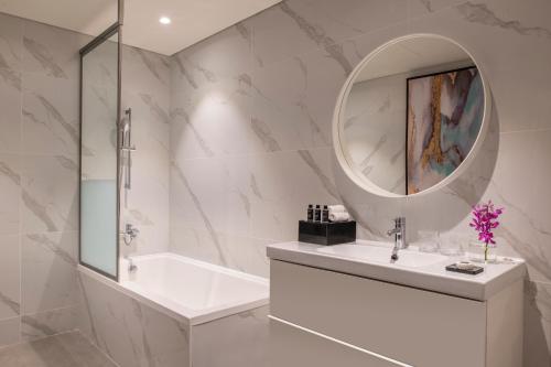 a bathroom with a tub and a sink and a mirror at Steigenberger Residence Doha in Doha