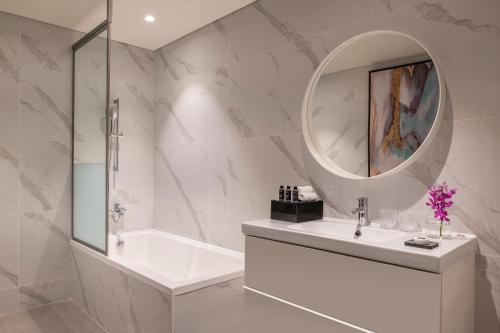 bagno con vasca, lavandino e specchio di Steigenberger Residence Doha a Doha