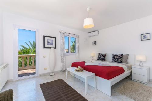 Habitación blanca con cama roja y balcón. en 2263 Sunny holiday home with views over the bay of Palma, en Badia Gran