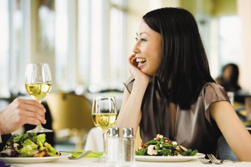 a woman sitting at a table with a plate of food and wine at Holiday Inn Shanghai Dishui Lake by IHG in Nanhui