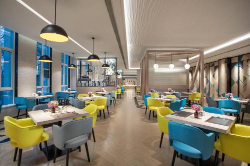 a restaurant with yellow and blue chairs and tables at Holiday Inn Shanghai Dishui Lake by IHG in Nanhui