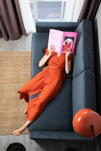 a woman laying on a couch reading a book at Bob W London Spitalfields in London