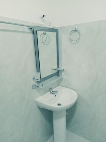 a white bathroom with a sink and a mirror at Kasun Hotel in Koslanda