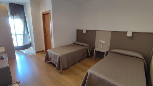 a hotel room with two beds and a window at Hotel Peña Cruz in Malpartida de Cáceres
