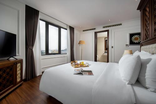 um quarto com uma grande cama branca e uma televisão em The Q Hotel em Hanói