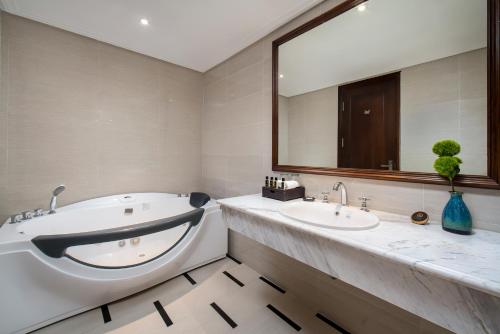 a bathroom with a tub and a sink and a mirror at The Q Hotel in Hanoi