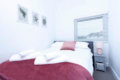 a bedroom with a white bed with a red blanket at Magnolia cove in Whitstable