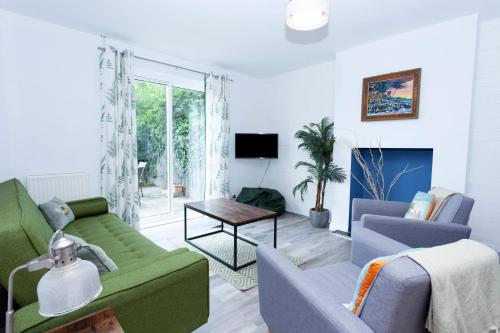 a living room with a green couch and two chairs at Magnolia cove in Whitstable