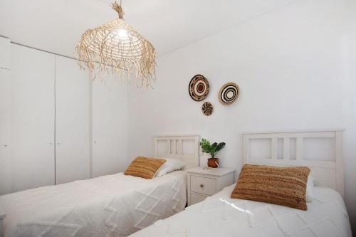 een witte slaapkamer met 2 bedden en een kroonluchter bij Luxury Boho Style Apartment Nazaré in Nazaré