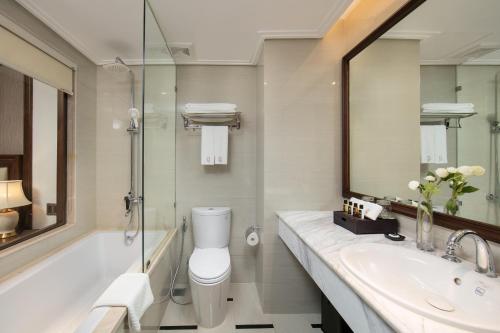 a bathroom with a toilet and a sink and a mirror at The Q Hotel in Hanoi
