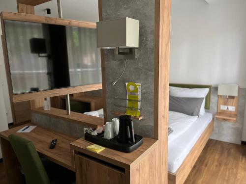 een kamer met een bed en een bureau met een koffiezetapparaat bij Hotel Knotenpunkt in Meppen