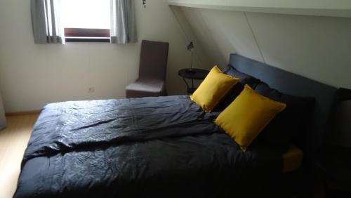 1 dormitorio con 1 cama con 2 almohadas amarillas en Chalet met wellness, en Lanaken