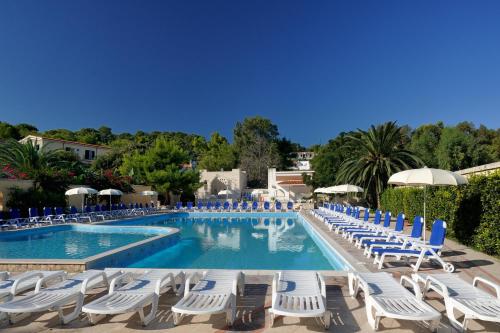 a swimming pool with lounge chairs and umbrellas at Baia Degli Aranci Suite & Apartments in Vieste