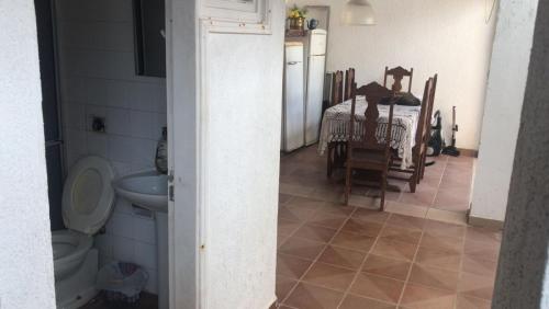 a bathroom with a toilet and a kitchen with a table at Hostel Pé na Areia in Itanhaém