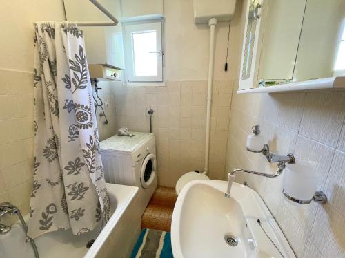 a bathroom with a sink and a toilet and a shower curtain at Apartman Asta in Jadranovo