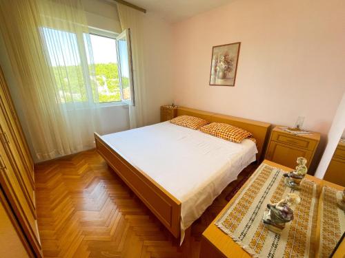 a small bedroom with a bed and a window at Apartman Asta in Jadranovo