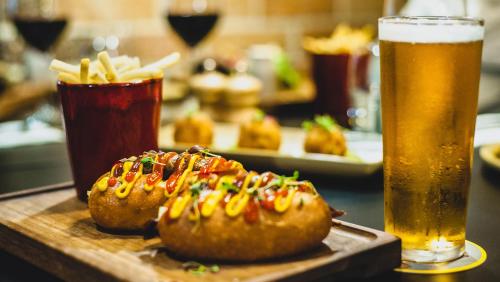 a table with two hot dogs and a glass of beer at Holiday Inn Perth City Centre by IHG in Perth