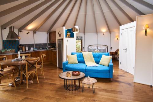 a living room with a blue couch and a kitchen at Woodpecker Treehouse in Dittisham