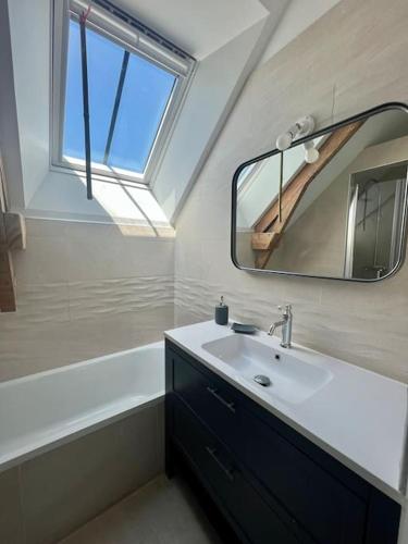 une salle de bain avec un lavabo, un miroir et une baignoire dans l'établissement Villa Salicorne, à Quiberon