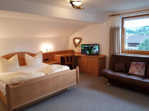a bedroom with a bed and a couch and a television at Alpenlandhaus in Pfronten