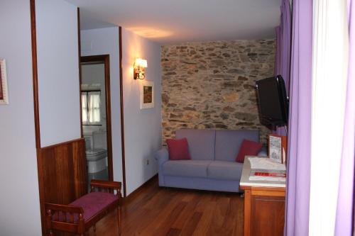 a living room with a blue couch and a tv at Hotel Casa Prendes in Cudillero