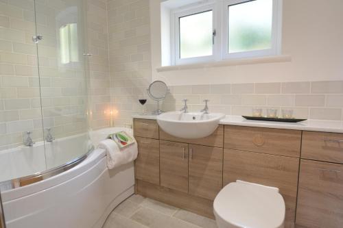 a bathroom with a tub and a sink and a toilet at Woodland Lodge, Aldeburgh in Aldeburgh