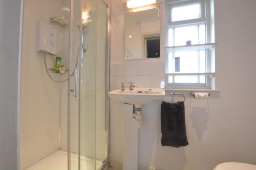 a white bathroom with a sink and a shower at Crabbe House in Aldeburgh