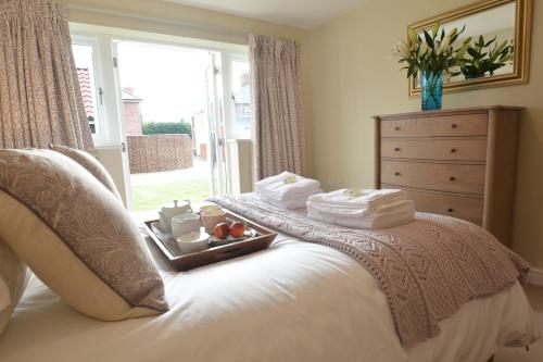 a bed with a tray of towels and a window at Woodland Lodge, Aldeburgh in Aldeburgh